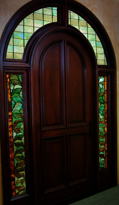 Transom windows are arched above a door with sidelights on either side